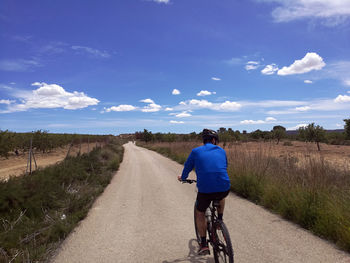 Rear view of man riding bicycle on road