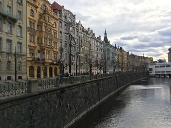 Bridge over river by buildings in city against sky