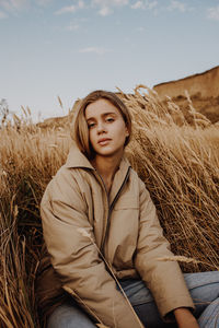 Portrait of beautiful woman in field against sky