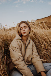 Portrait of beautiful woman in field against sky