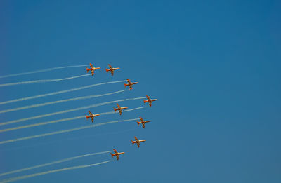 Low angle view of airshow against clear blue sky