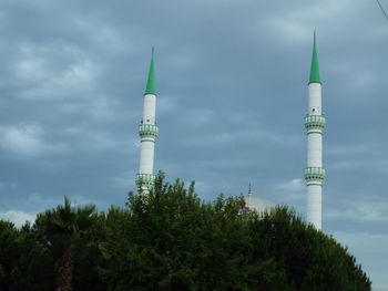 Trees and mosque against sky