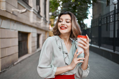 Young woman using phone while standing in city