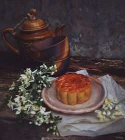 Close-up of food in plate by flowers and teapot on table