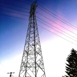 Low angle view of electricity pylon against cloudy sky