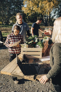 Female farmer selling organic vegetables to customers at market