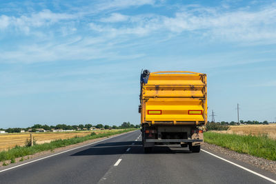 Yellow road amidst field against sky