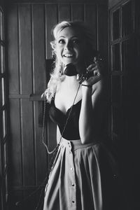 Smiling woman looking sway while holding payphone