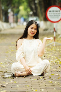 Portrait of young woman sitting on boardwalk