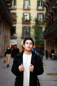 Portrait of young man standing on street in city