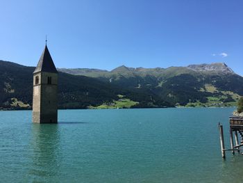 Scenic view of lake by building against clear blue sky