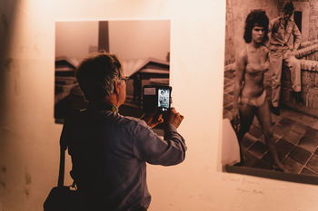 REAR VIEW OF MAN PHOTOGRAPHING AT HOME