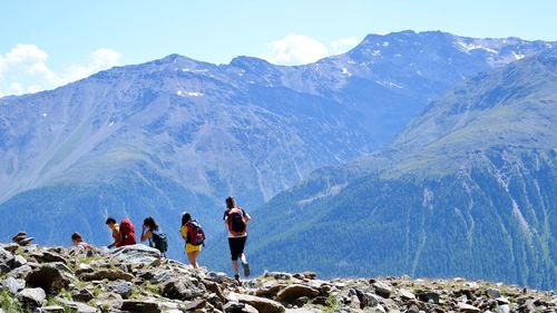 People hiking on mountain against sky