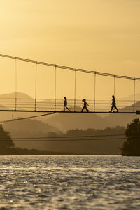 Bridge over sea against sky during sunset