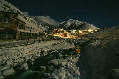 Illuminated houses by snowcapped mountains against sky at night snow, cold, frost, fox house river
