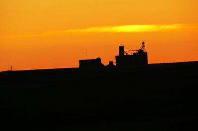 Silhouette building against orange sky