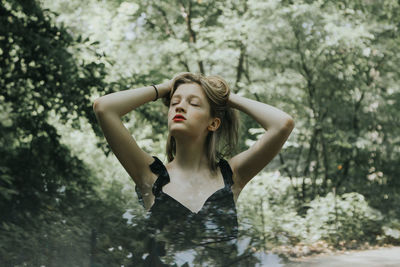 Woman with arms raised standing against trees