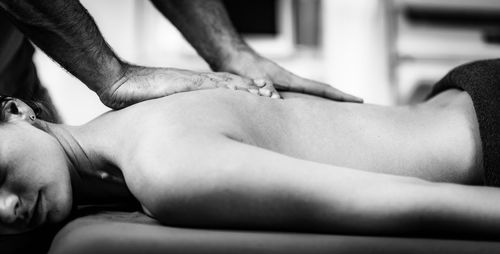 Male physical therapist massaging female clients back muscle.