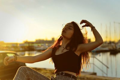 Woman posing outdoors against sky during sunset