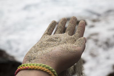 Close-up of hand holding sand at beach