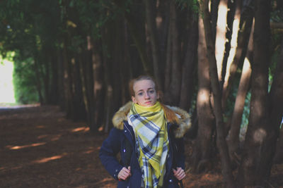 Portrait of smiling young woman standing in forest