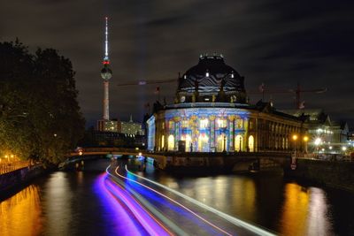 Illuminated buildings by river at night