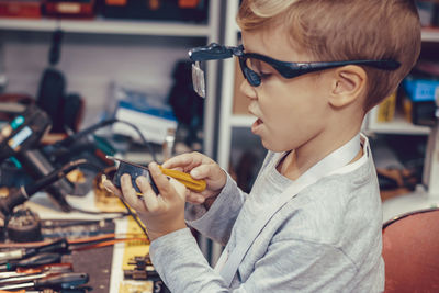 Small kid experimenting with magnet and work tools during in science workshop.