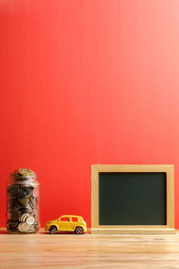 Toy car on table against red wall