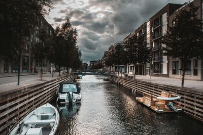 Canal amidst buildings in city against sky