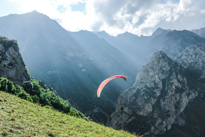 People paragliding on mountain peak against sky