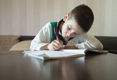 Side view of boy sitting on table