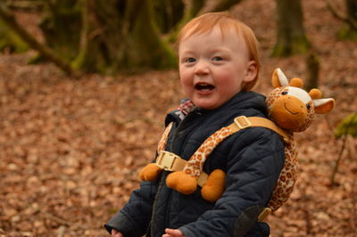 Close-up of cute boy sitting on autumn leaves