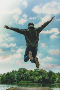 Rear view of man jumping against sky
