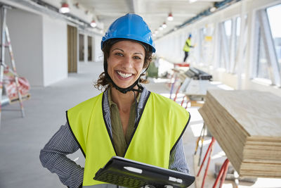 Portrait of smiling female engineer with digital tablet standing at construction site