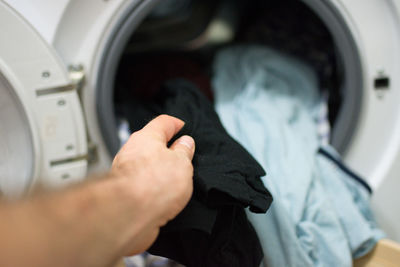 Cropped hand of man washing clothes in machine