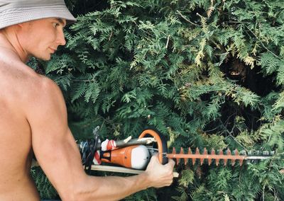 Midsection of shirtless man holding woman in yard