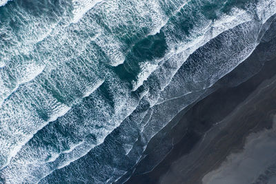 Aerial view of sea waves washing black sandy beach. hofn, iceland