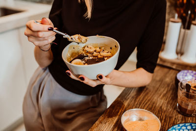 Cropped hand of woman eating dessert at kitchen