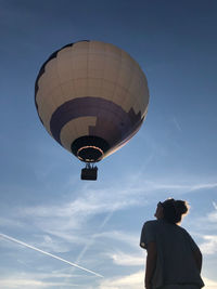 Low angle view of woman looking at hot air balloon against sky