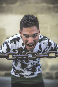 Portrait of young man screaming by chain