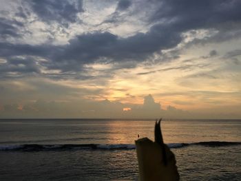 Silhouette man on sea against sky during sunset