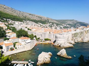 High angle view of townscape by sea against clear sky