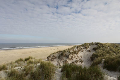 Scenic view of calm beach against cloudy sky