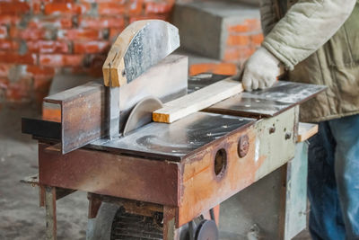 A carpenter cuts wood with a circular saw in a carpenter's shop