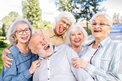 Portrait of smiling friends standing against sky