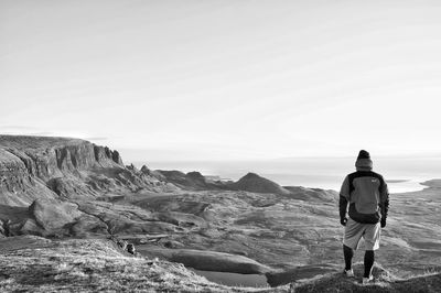 Rear view of man walking on mountain against sky