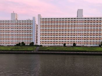 View of buildings by river against sky