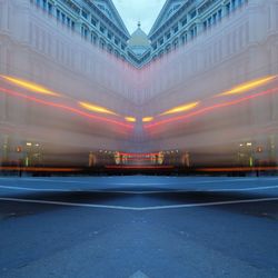 Light trails on road against illuminated buildings in city at night