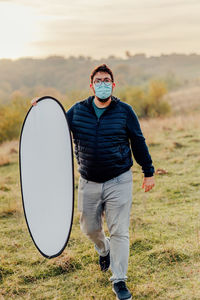 Full length of man photographer standing on field against sky