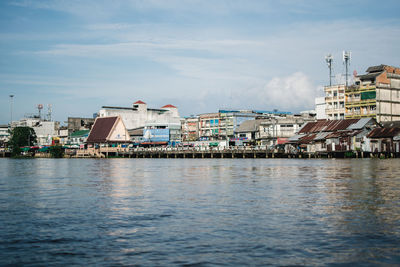 Buildings by sea against sky